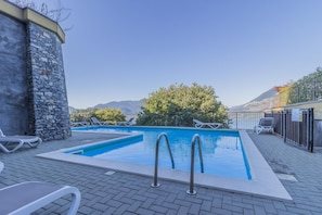 A rectangular outdoor swimming pool with two ladders, surrounded by lounge chairs and a stone wall. - Palma Romantic Dream (Perledo)