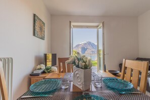 Un coin repas avec vue sur la montagne, un vase rempli de fleurs et un téléviseur posé sur la table.