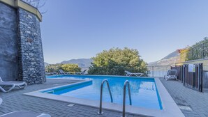 A rectangular pool with two ladders, surrounded by a stone wall and a paved deck. - Palma Romantic Dream (Perledo)