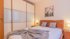 A neatly made bed with a gray blanket, a wooden headboard, and a nightstand with a lamp. - Patrizia s House Varenna (Varenna)