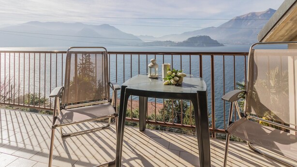 A balcony with a table, chairs, and a view of a lake and mountains. - Patrizia s House Varenna (Varenna)