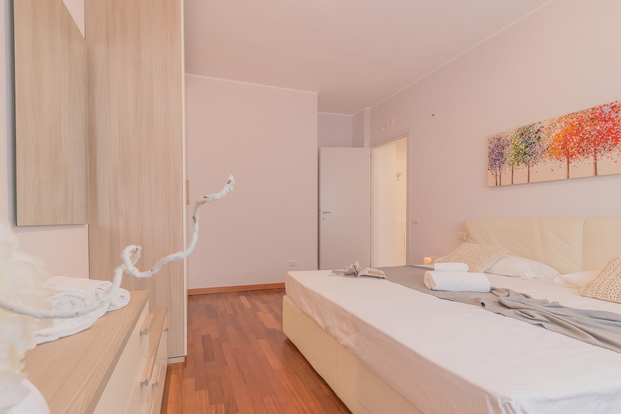 A bedroom with a bed, a bedside table, a wardrobe, and a painting on the wall.