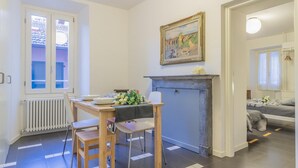 A dining area with a table set for two, a fireplace, and a painting above it. - La Casa di Rosa in Varenna (Varenna)