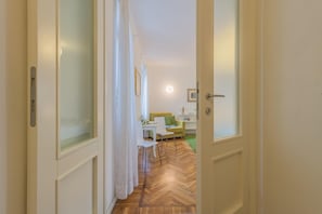 Enter a serene space with a green sofa, white table, and cabinet, surrounded by frosted glass panels and a picture frame.