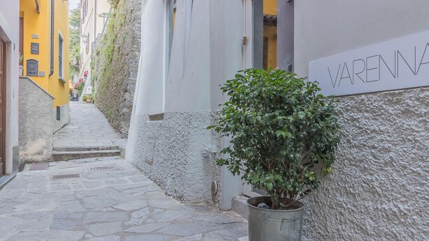 A narrow stone-paved alley with a potted plant and a building with a sign reading "RENNA". - La Casa di Rosa in Varenna (Varenna)