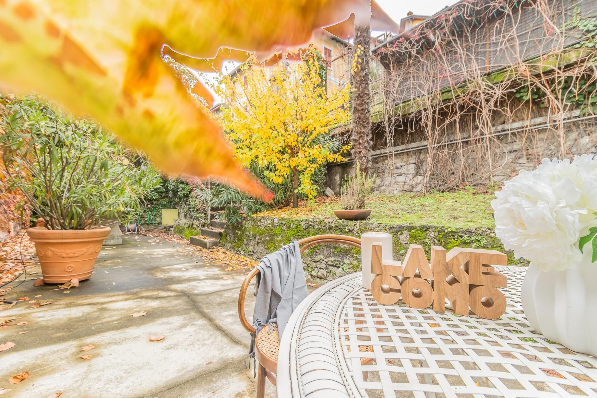 A garden with a table displaying the word "LAKE" and a white flower.