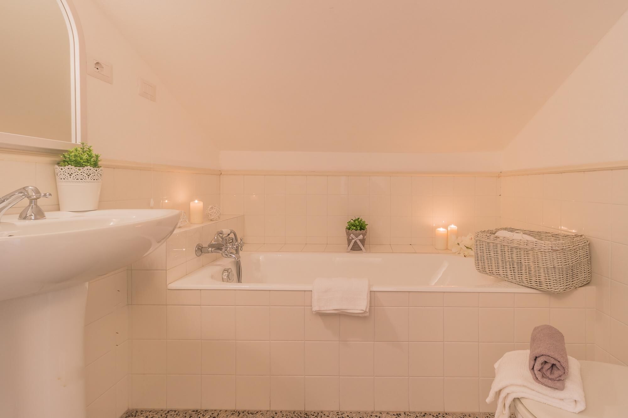 Une salle de bain avec un lavabo, un miroir, une baignoire et deux plantes en pot.