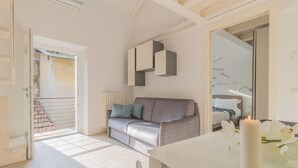 Una sala moderna con un sofá gris, una mesa blanca y una vela encendida.