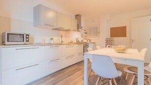A modern kitchen with white cabinetry, a microwave, and a dining table with chairs.