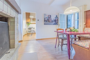 Un salon moderne avec une cheminée, un coin repas avec une table et des chaises, et une cuisine visible au fond.