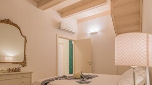 Une chambre à coucher comprenant un lit, une commode, un miroir et un appareil de climatisation.