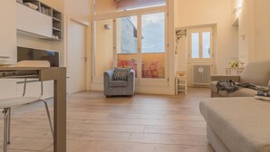 Un salon moderne comprenant un canapé, un coin repas avec des chaises et un espace cuisine avec des étagères.
