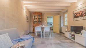 Un espace de vie compact comprenant un canapé, une table à manger avec des chaises, un coin cuisine et un téléviseur posé sur un meuble.