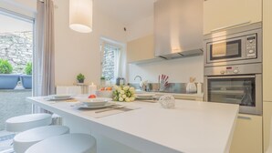 Una cocina moderna con una isla central, electrodomésticos de acero inoxidable y vistas al exterior.