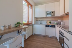 A modern kitchen with white cabinets, a built-in microwave, a dishwasher, and a wooden countertop. - La Maison du Lac in Varenna (Varenna)