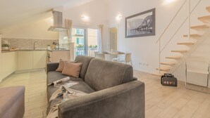 Ein modernes Wohnzimmer mit Sofa, Essbereich und einer Treppe.