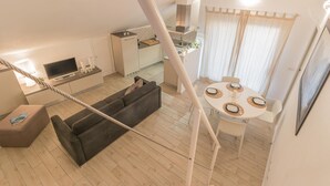 Eine moderne Wohnung mit Wohnbereich, Küchenzeile, Esstisch und Balkon.