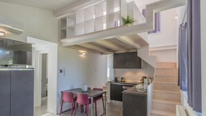 A modern kitchen with a dining area, a staircase, and a small balcony. - La Terrazza di Marta (Varenna)