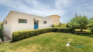 A two-story house with a flat roof, a blue door, and a small window on the upper floor. - Sr-f943-gmar0bct - Country Chic (Noto)