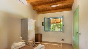 A bedroom with a wooden ceiling, a bed with a metal frame, a wardrobe, a small cabinet, and a green door. - Sr-f943-gmar0bct - Country Chic (Noto)
