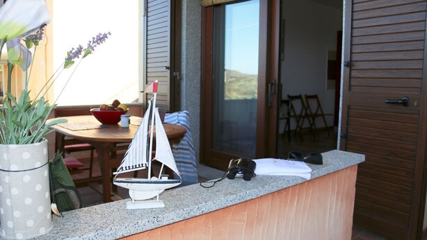 Ein Balkon mit einem kleinen Modell eines Segelboots, einer Obstschale und einem Blumentopf.
