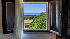 A window with an open view of a landscape, including trees and a distant body of water. - b Giagumeddu 10A Bilo (Badesi)