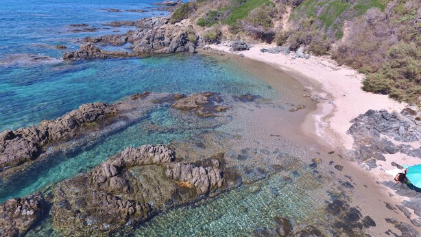 A coastal beach with clear waters, rocky formations, and a sandy shoreline. - b Giagumeddu 10A Bilo (Badesi)