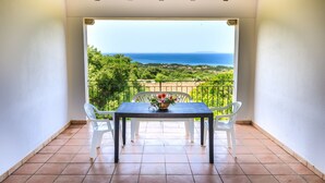A balcony with a table and chairs, overlooking a scenic view of the sea and greenery. - b Giagumeddu 10A Bilo (Badesi)