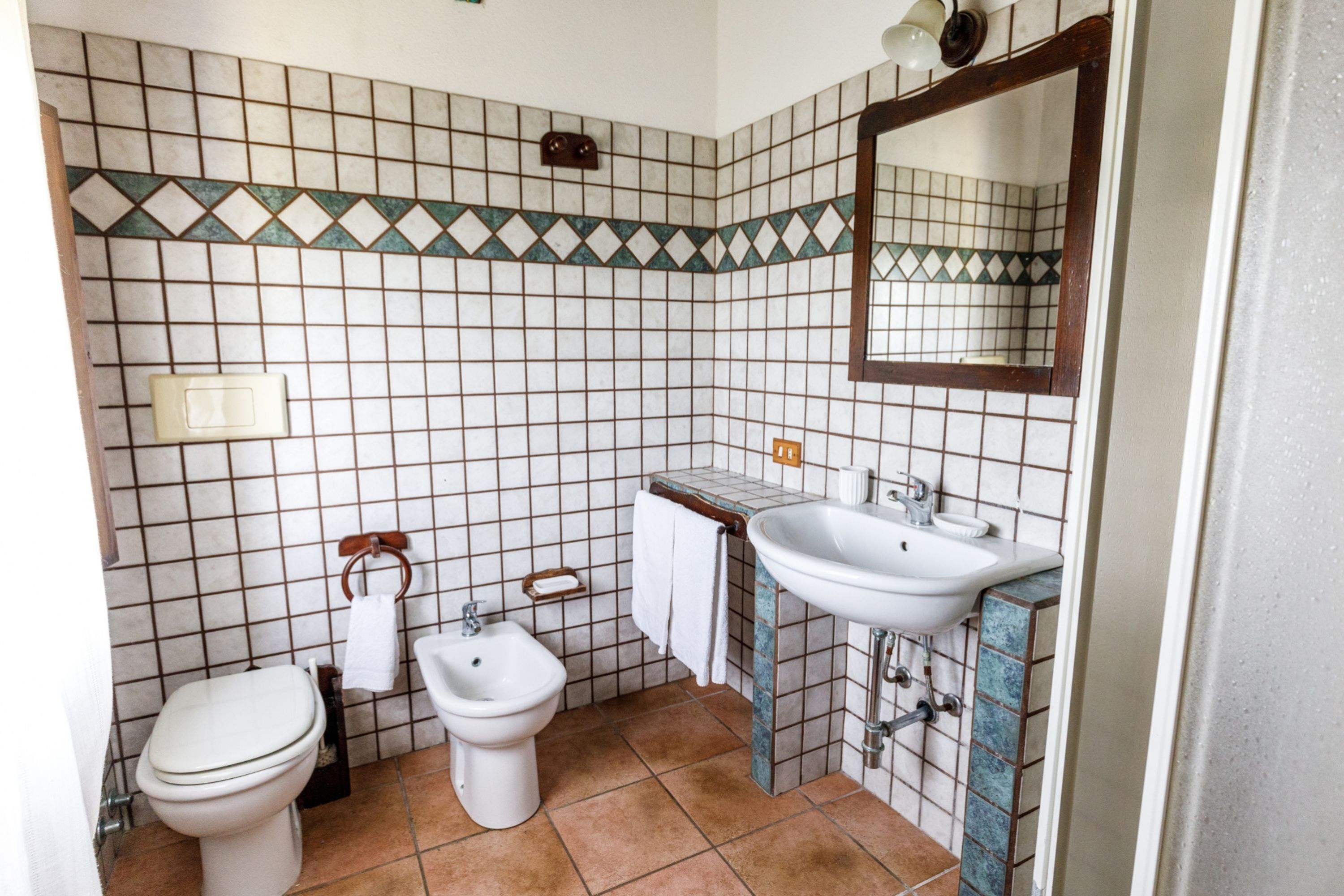 Une salle de bain équipée de toilettes, d’un bidet, d’un lavabo et d’un miroir.