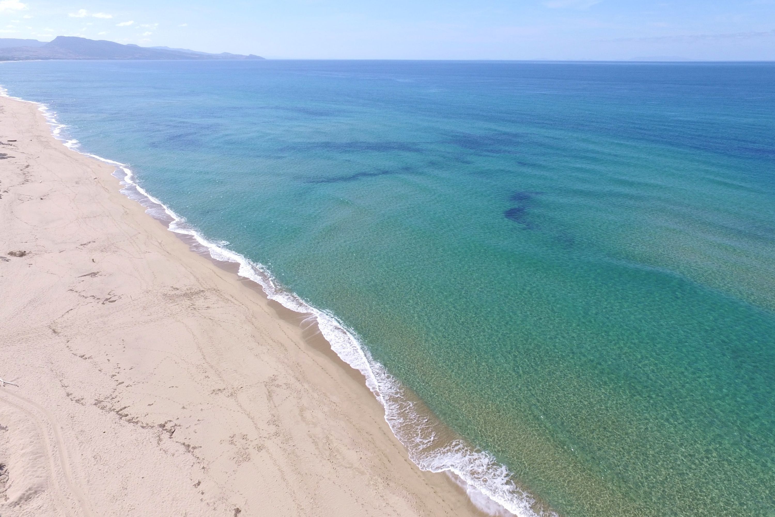 Ein Strand mit klarem türkisblauem Wasser und einem sandigen Ufer.