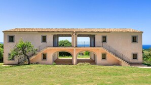 A two-story building with a tiled roof, a central archway, and a staircase leading to an upper level. - b Giagumeddu 08A Bilo (Badesi)