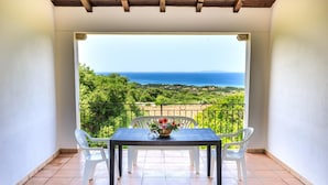A balcony with a table and chairs, overlooking a scenic view of the sea and greenery. - b Giagumeddu 07A Bilo (Badesi)