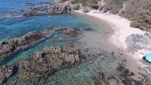 A coastal landscape with clear waters, rocky shorelines, and a sandy beach. - b Giagumeddu 07A Bilo (Badesi)