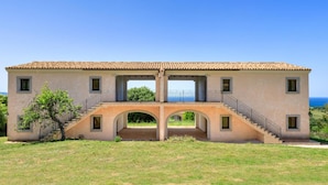 A two-story building with a central archway and a staircase leading to the upper floor. - b Giagumeddu 07A Bilo (Badesi)