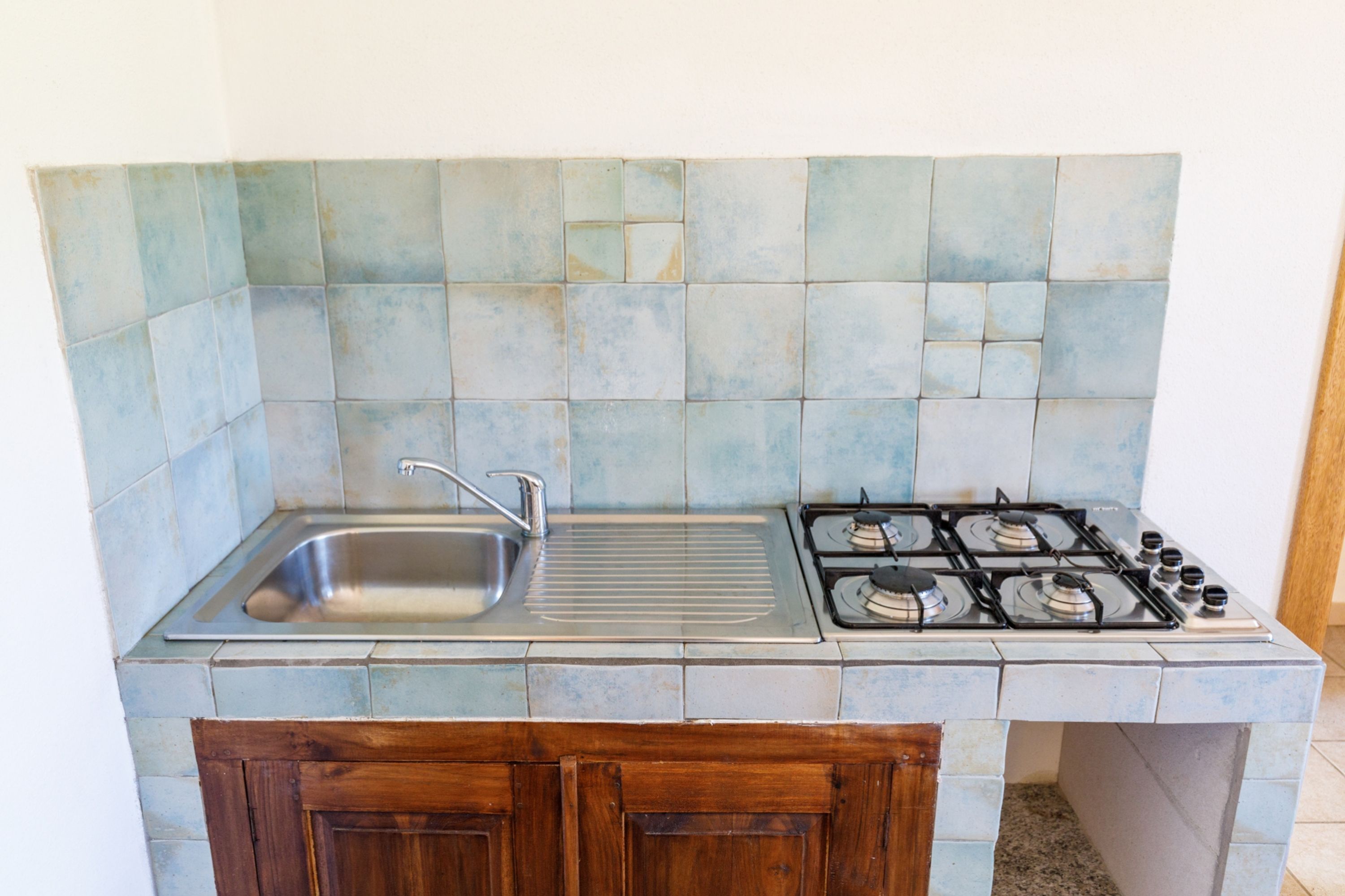 A kitchen with a stainless steel sink, a gas stove, and a tiled backsplash.