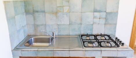 A kitchen with a stainless steel sink, a gas stove, and a tiled backsplash.