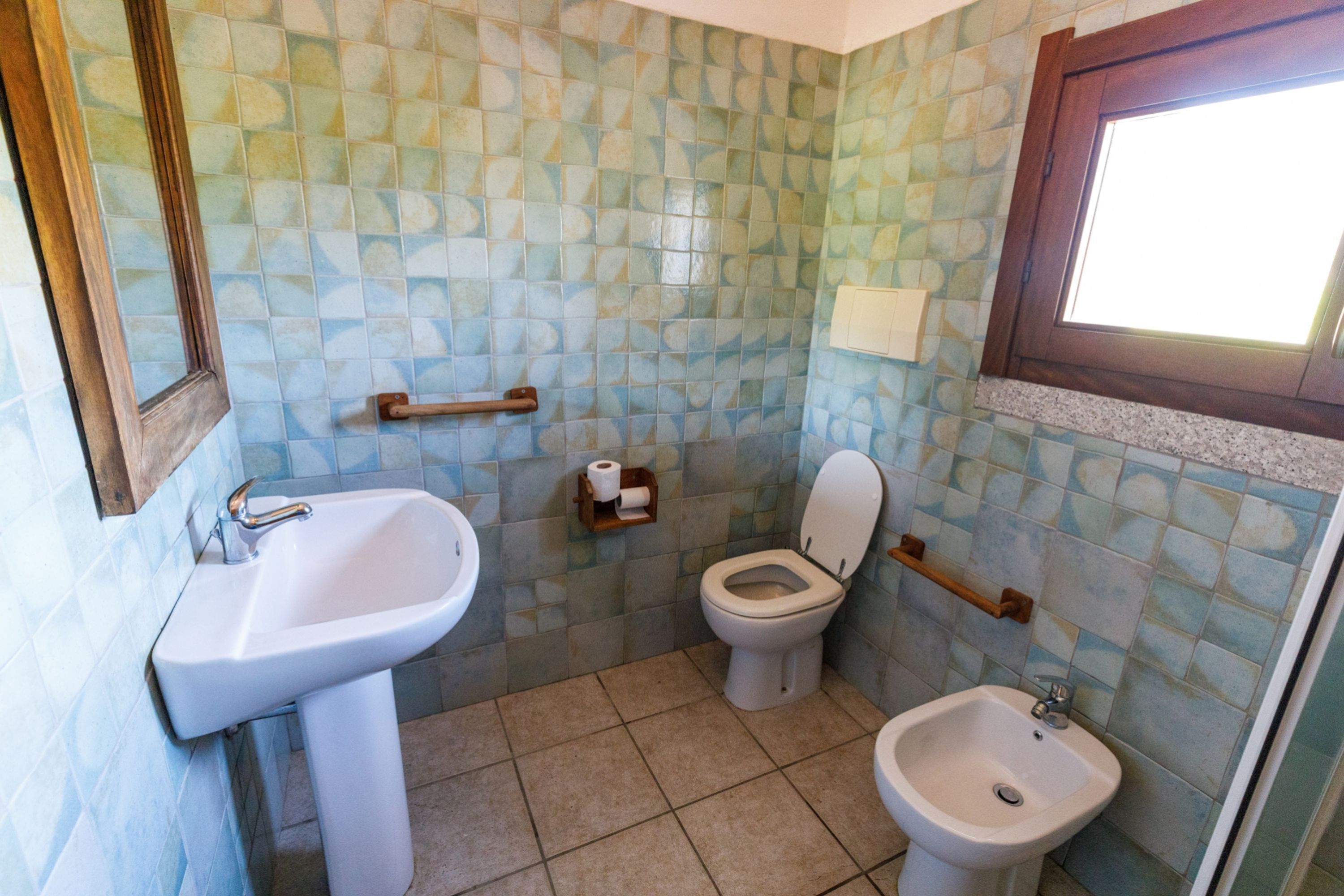 A bathroom with a sink, toilet, and bidet.
