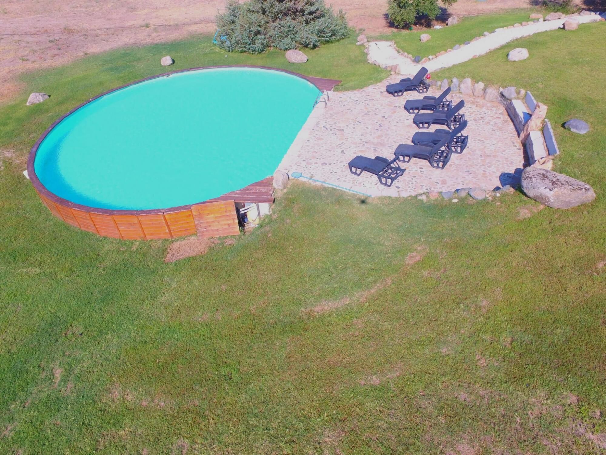 Vista aérea de una piscina con cubierta de madera y sillones de descanso.