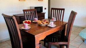 A dining table with chairs, a basket of fruit, and two mugs. - d Pietraia 13B Trilo (Badesi)