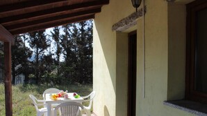 A covered patio with a table and chairs, a window, and a door. - d Pietraia 13B Trilo (Badesi)