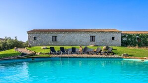 A stone building with a tiled roof, a swimming pool, and lounge chairs. - d Pietraia 13B Trilo (Badesi)
