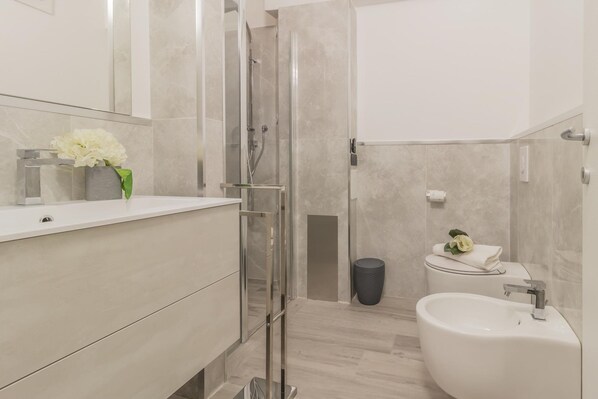 Un baño moderno con cabina de ducha de vidrio, un lavamanos blanco y un inodoro.
