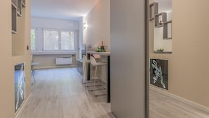 Moderni keittiö, jossa on valkoiset kaapit, baaritiski jakkaroineen ja seinällä oleva neonvalomainos.