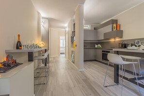 Una cocina moderna con una isla central, taburetes de bar y una botella de vino en la encimera.