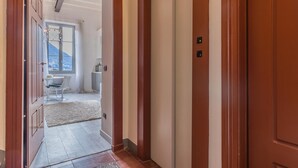 Un couloir avec des portes en bois, un tapis blanc et une vue sur un coin repas avec une table et des chaises.