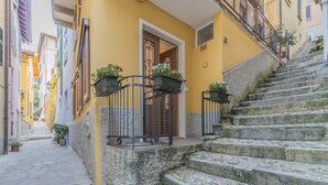 Eine enge Straße mit einem gelben Gebäude, Steinstufen und Blumenkästen an der Brüstung.