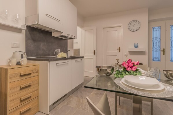 Enjoy a contemporary kitchen with a sleek countertop, white cabinetry, and a glass dining table.