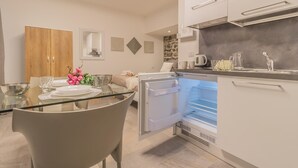 Eine moderne Küche mit integriertem Kühlschrank, einem Esstisch mit Stühlen und einem Holzkasten.