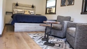 A bedroom with a bed, a desk, and two chairs.