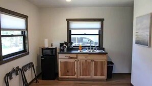 A compact kitchen with wooden cabinets, a microwave, and a window above the sink.